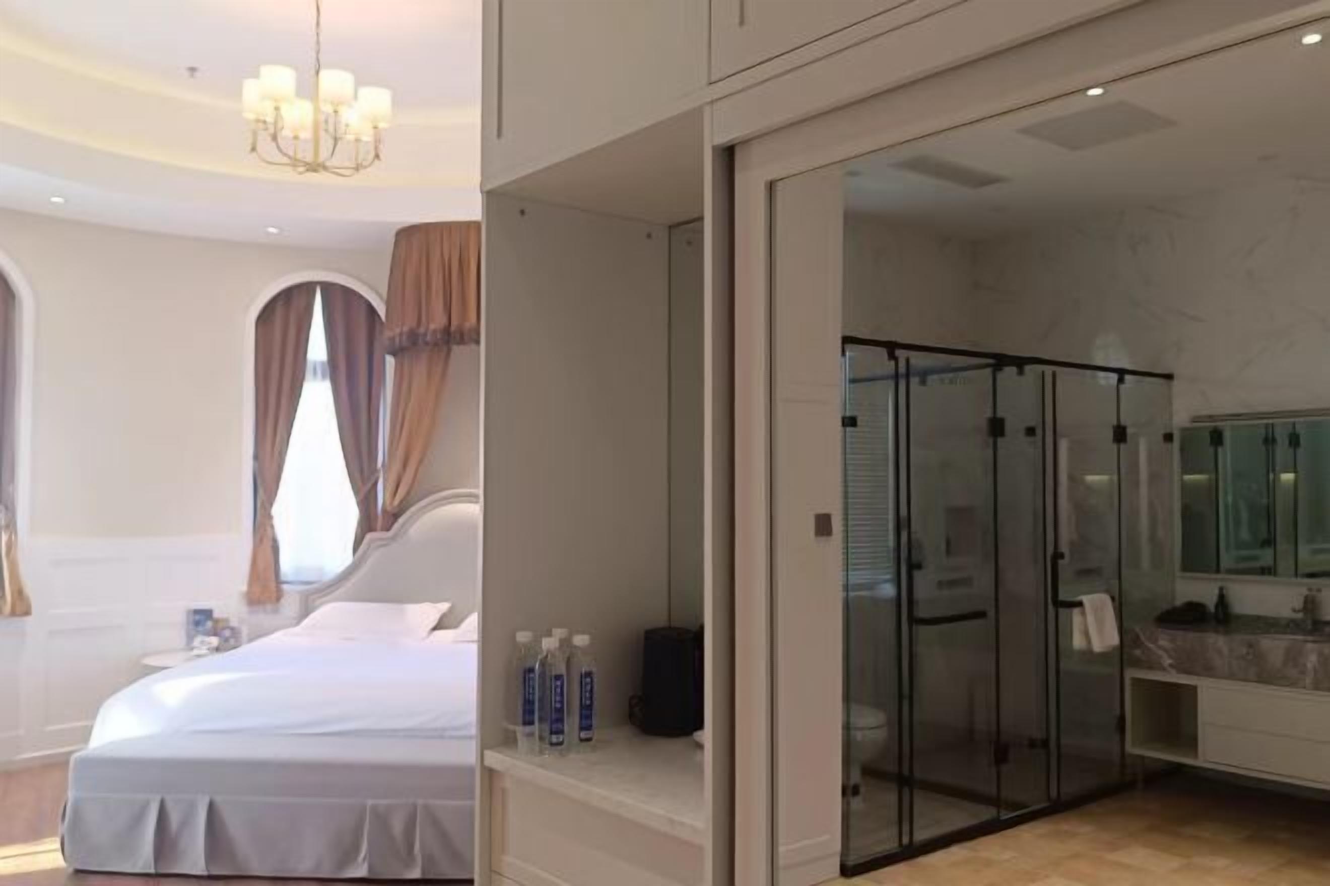 A modern hotel room with a large bed, a glass-enclosed shower, and a bathroom with a marble countertop.