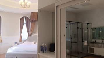 Habitación de hotel moderna con una cama grande, cabina de ducha con paredes de vidrio y baño con encimera de mármol.