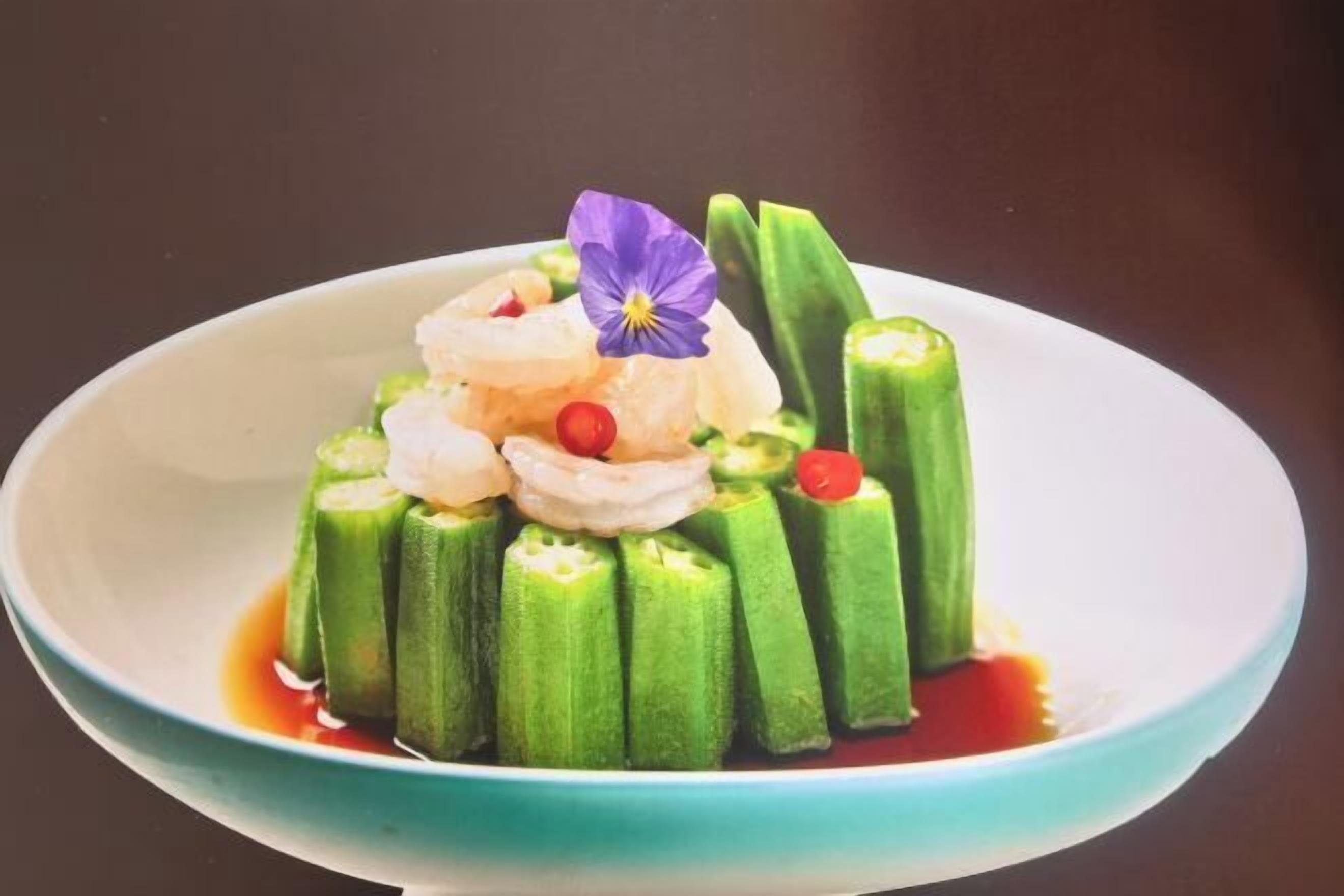A bowl of food with okra and a flower garnish.