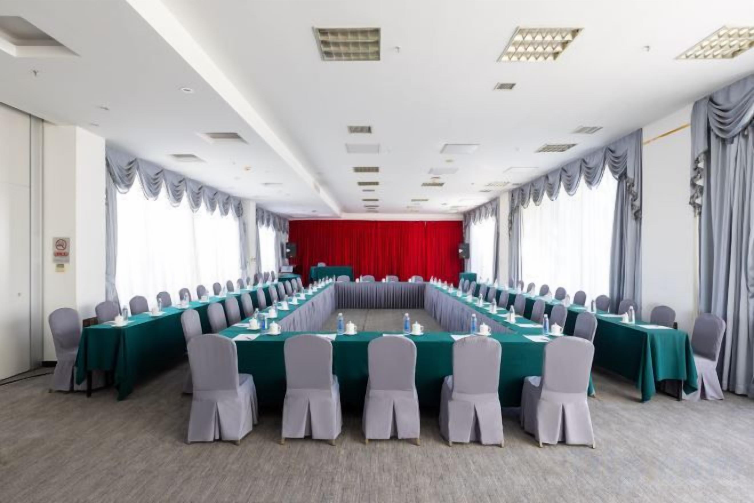 A conference room with a long table, chairs, and a stage.