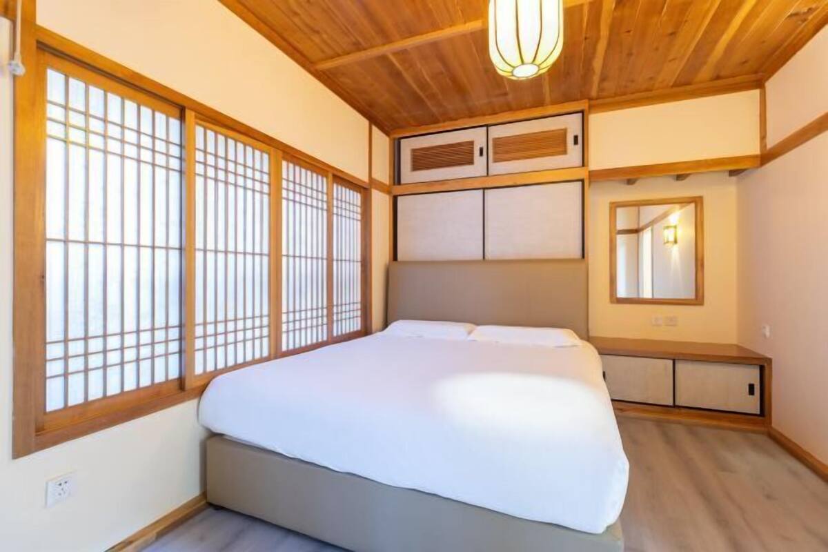 Ein Schlafzimmer mit Bett, Holzboden, Schiebetüren und einem Nachttisch.