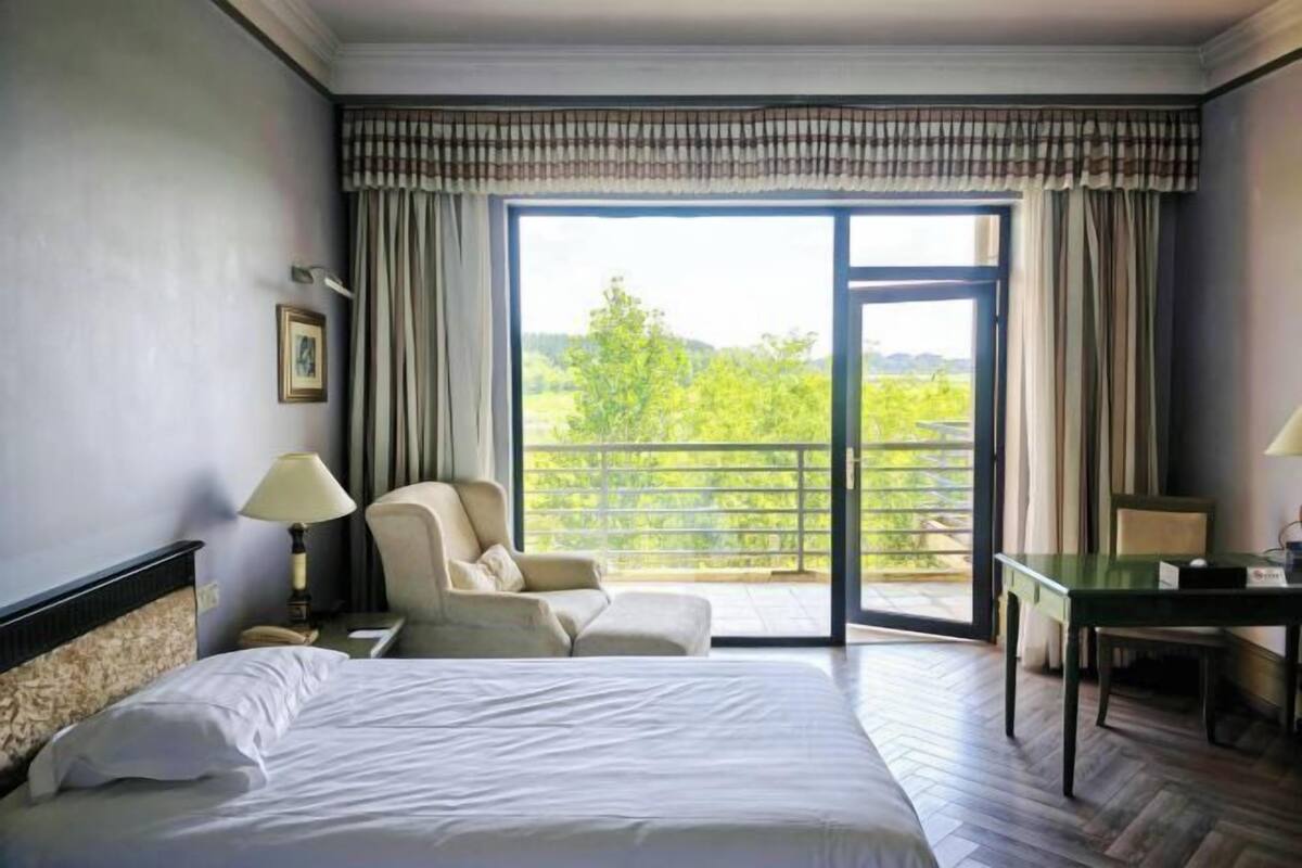 Ein Hotelzimmer mit Bett, einem Sessel, einem Tisch und einem Balkon mit Aussicht.