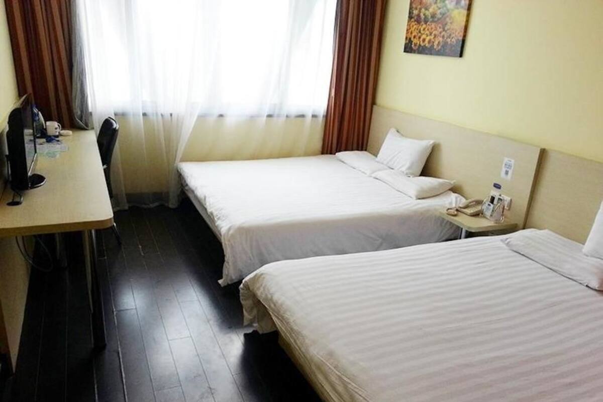 A hotel room with two single beds, a desk, and a chair.