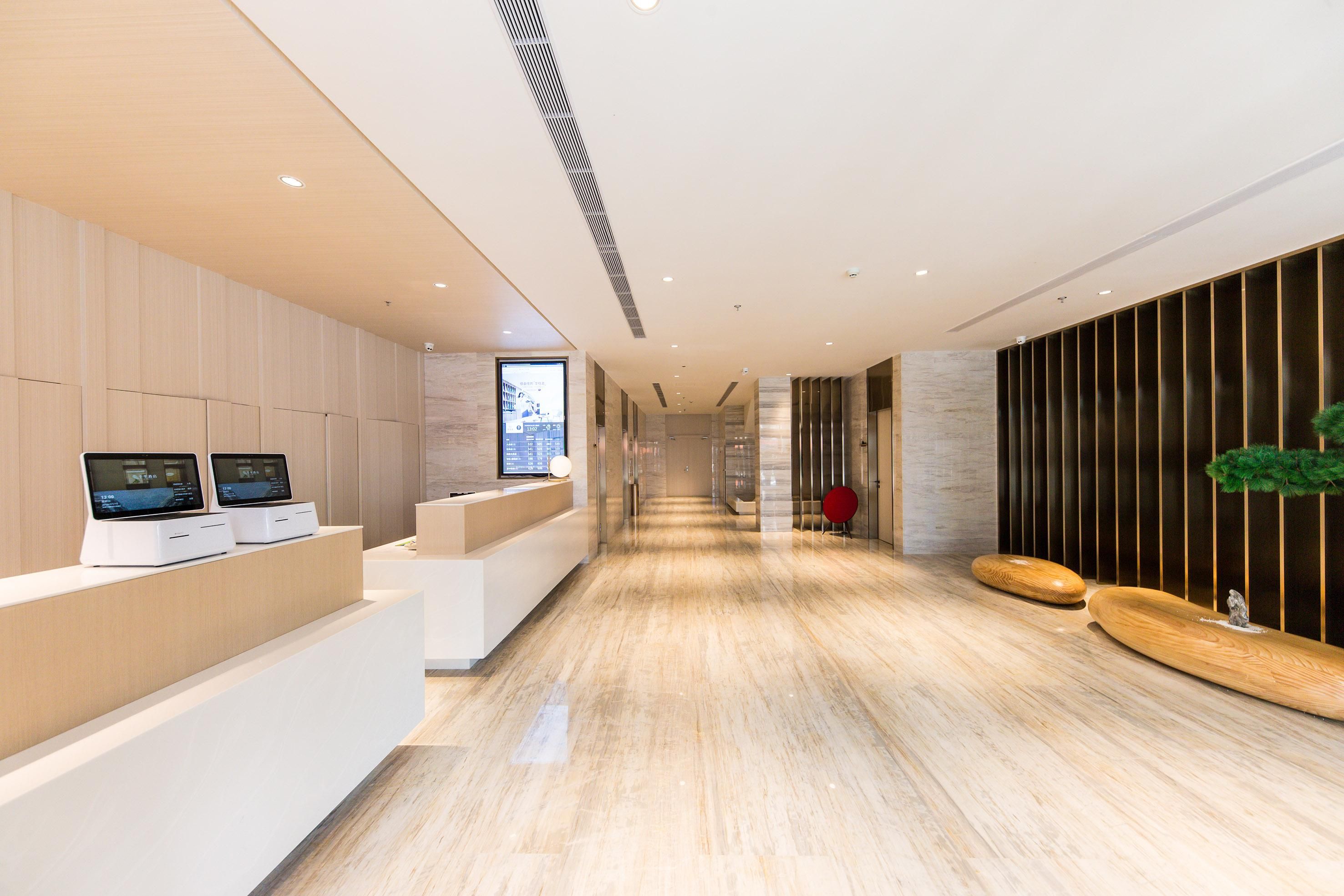 A modern reception area with a long corridor, a reception desk, and a digital display.