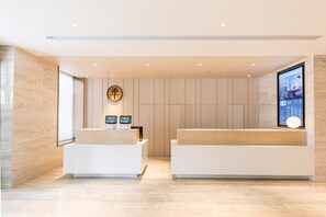 Un espace d’accueil moderne, doté de deux comptoirs de réception blancs, d’un écran numérique et d’un mur revêtu de panneaux en bois.