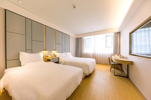 A hotel room with two beds, a desk, and a large window.
