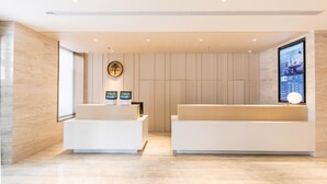 A modern reception area with two white reception desks, a digital screen, and a wooden panel wall.