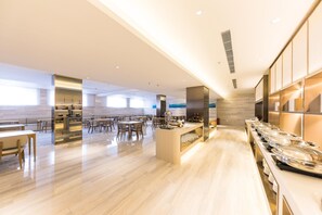 A spacious hotel dining area with a long counter, multiple tables, and a modern interior design. - Ji Hotel Dalian Xinghai Park (Dalian)