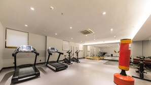 A gym with treadmills, elliptical machines, and a punching bag.