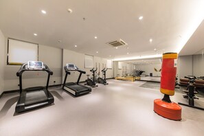 A gym with treadmills, elliptical machines, and a punching bag.