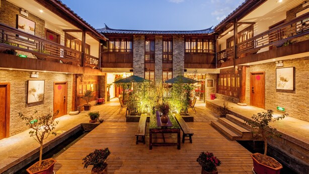 A traditional courtyard with wooden benches, potted plants, and a central table. - Liman Wenzhi No.1 Hotel Lijiang Ancient Town (Lijiang)