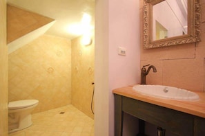 A bathroom with a toilet, a sink with a mirror, and a shower area. - Antique's home (Hengchun)