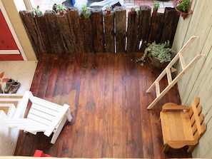 A wooden deck with a wooden fence, potted plants, a white chair, and a wooden bench. - Antique's home (Hengchun)