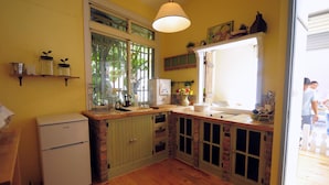 Une cuisine de taille réduite, équipée d’un réfrigérateur, d’un évier et de meubles de rangement en bois.