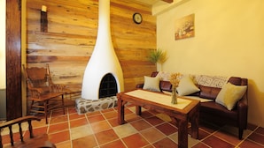 Un salon chaleureux avec une cheminée en pierre, des murs en bois, un canapé en cuir et une table basse en bois.