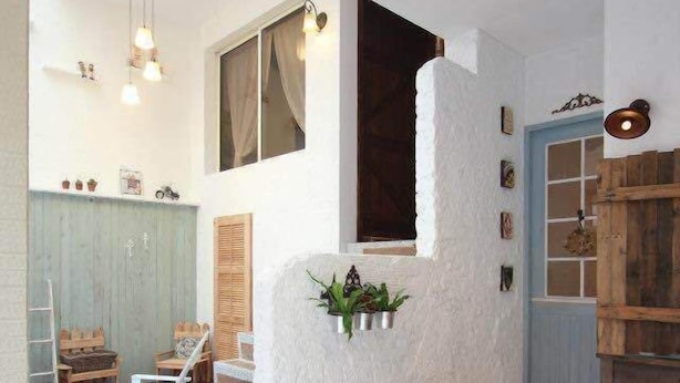 Un escalier menant à une chambre située en mezzanine, avec un mur blanc, un plancher en bois et un petit balcon.