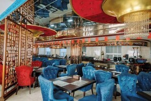 A restaurant with blue upholstered chairs, a red and gold ceiling, and a decorative wall.