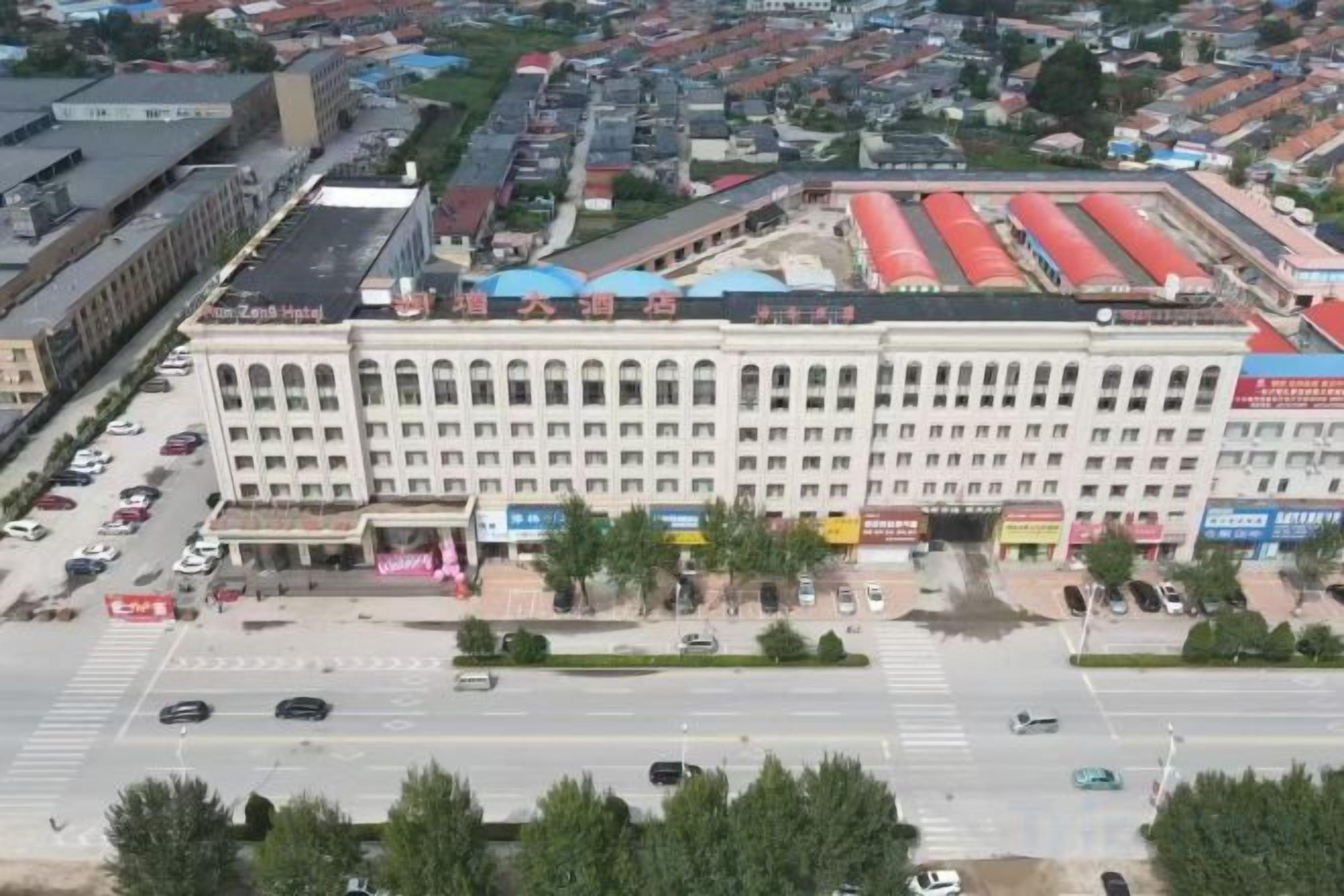 A multi-story building with a central entrance, surrounded by a parking lot and a street.