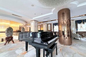 Ein Flügel in einer geräumigen, elegant gestalteten Lobby mit Marmorböden und einer großen, zylindrischen Säule.