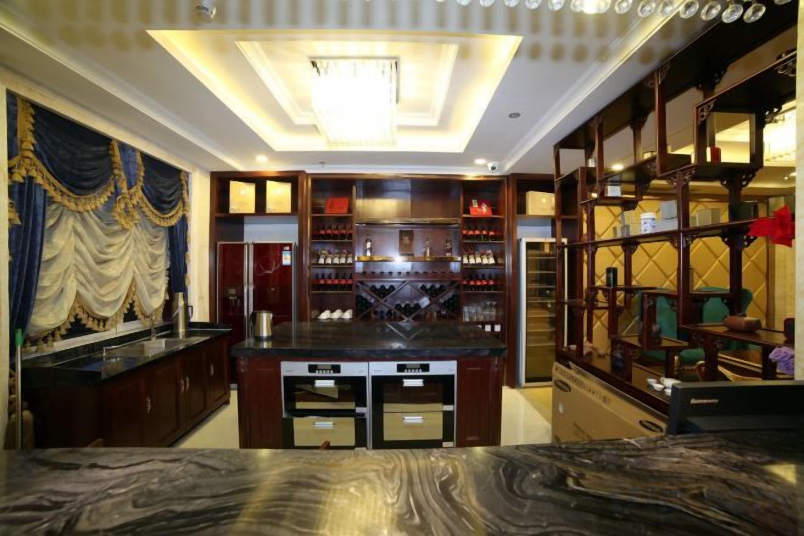 A hotel room with a marble countertop, a minibar, and a large mirror.