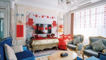 Una sala de estar tradicional con televisor, sofás y un decorativo mural.