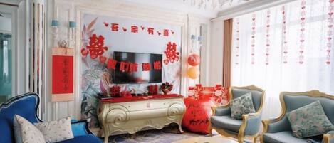 Ein traditionell eingerichtetes Wohnzimmer mit Fernseher, Sofas und einer Wanddekoration.