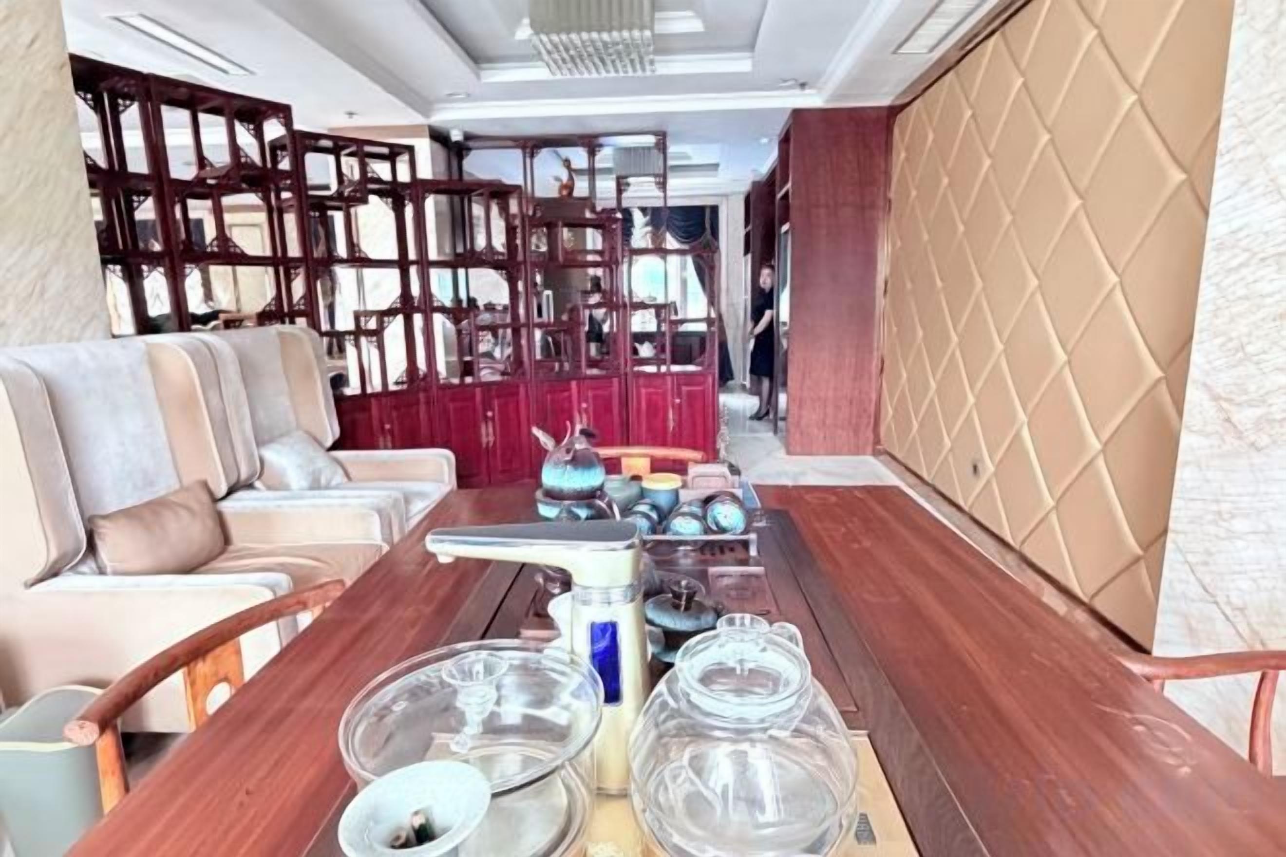 A room with a long wooden table, a sofa, and a decorative wall panel.