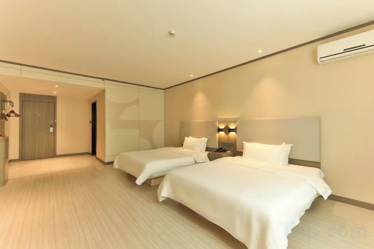 Une chambre d’hôtel avec deux lits, une table de chevet, une lampe et un miroir.