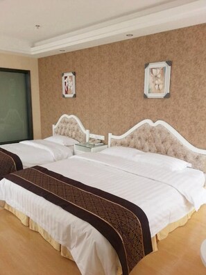 A hotel room with two beds, a bedside table, and a wall-mounted clock. - Xikelai Hotel (Qingdao)