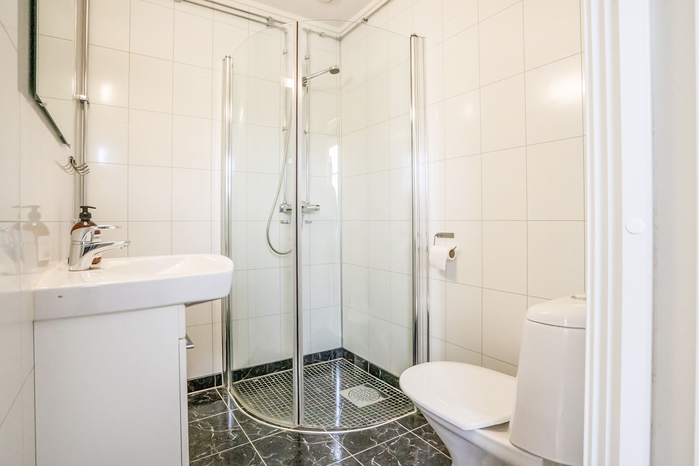 A modern bathroom with a glass-enclosed shower, a white sink, and a toilet.