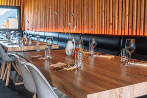 A restaurant with wooden tables, white chairs, and a wooden wall with vertical slats. - Topcamp Havblikk - Helgeland (Nesna)