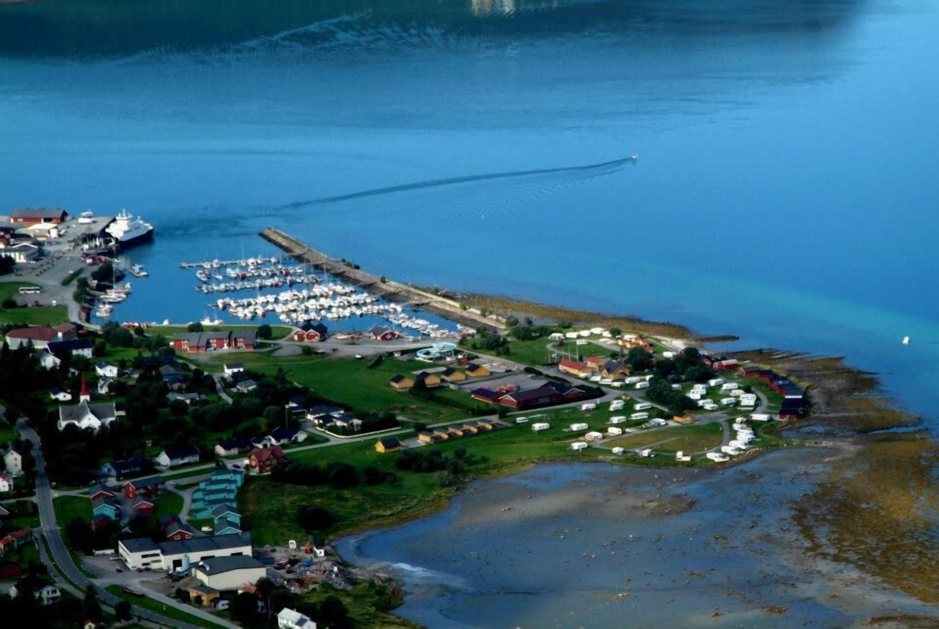 An aerial view of a coastal town with a marina, houses, and a small harbor.