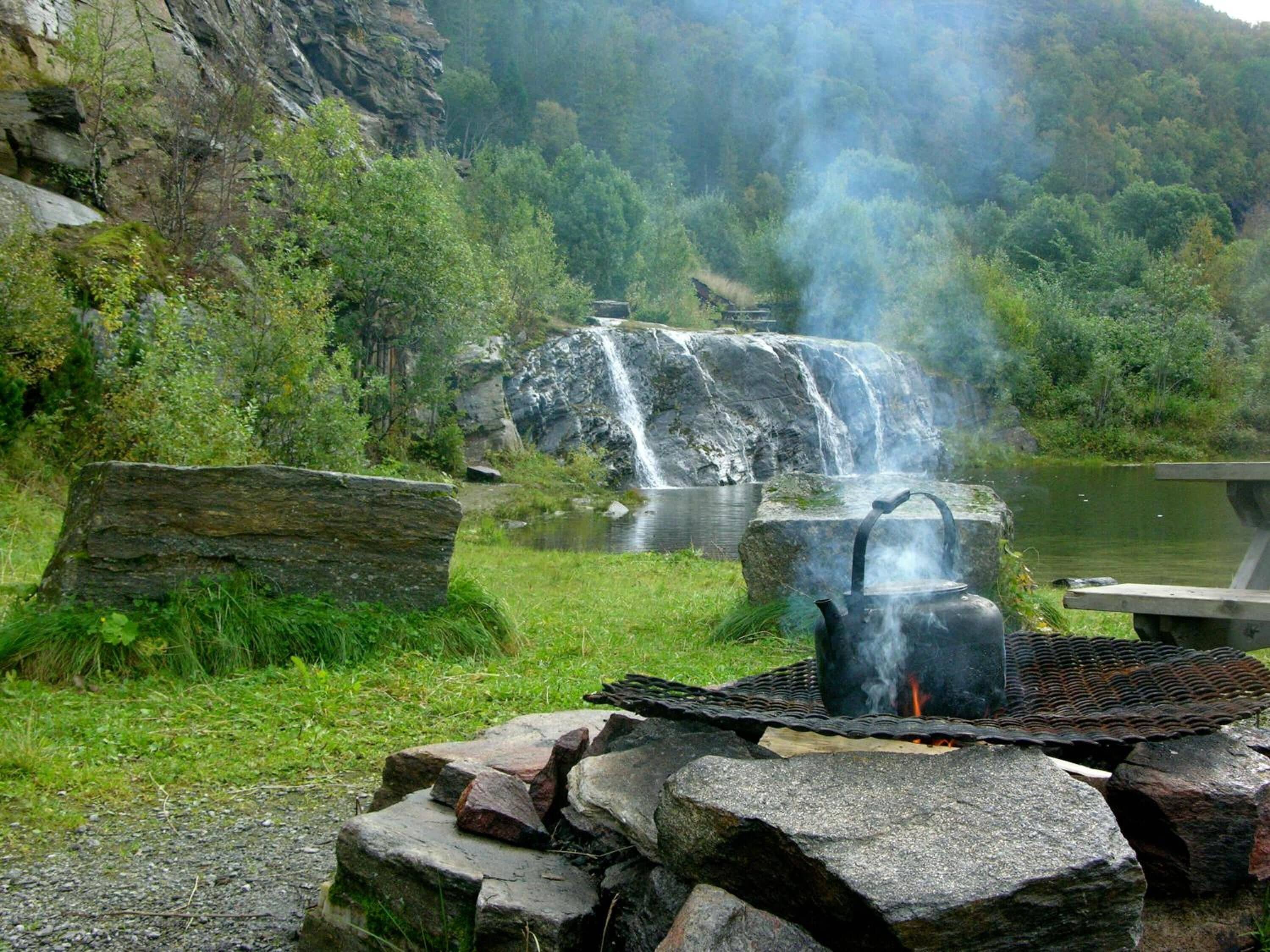 Un cadre extérieur rustique avec un foyer en pierre et une cascade en arrière-plan.