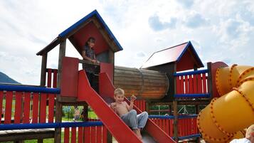 Kids can play and climb in the play structure with a slide, house-like shelter, and climbing tunnel.