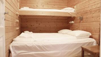 A small, wooden cabin-style room with a bunk bed, a single bed, and a small table.