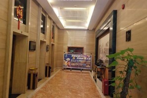 A hotel corridor with a marble floor, a reception desk, and a poster on the wall.