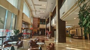 Eine großzügige Lobby mit hoher Decke, mehreren Sitzbereichen und einer Rezeption.