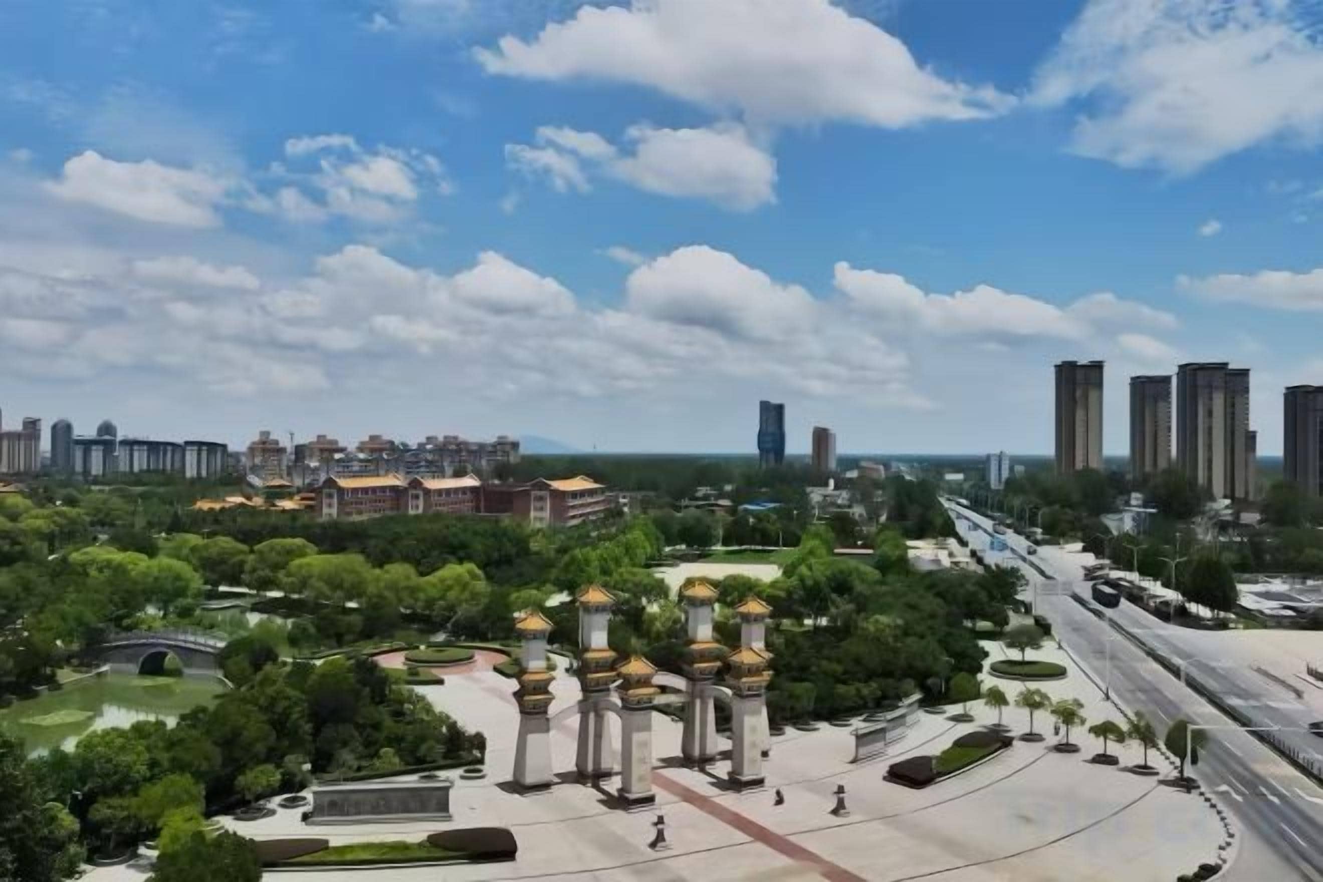 A park with a fountain, a monument, and a road with vehicles.
