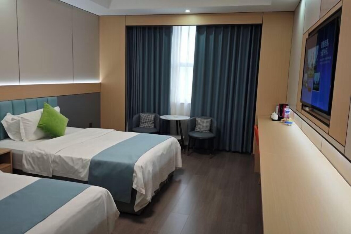 Una habitación de hotel con dos camas, una mesita y un televisor.