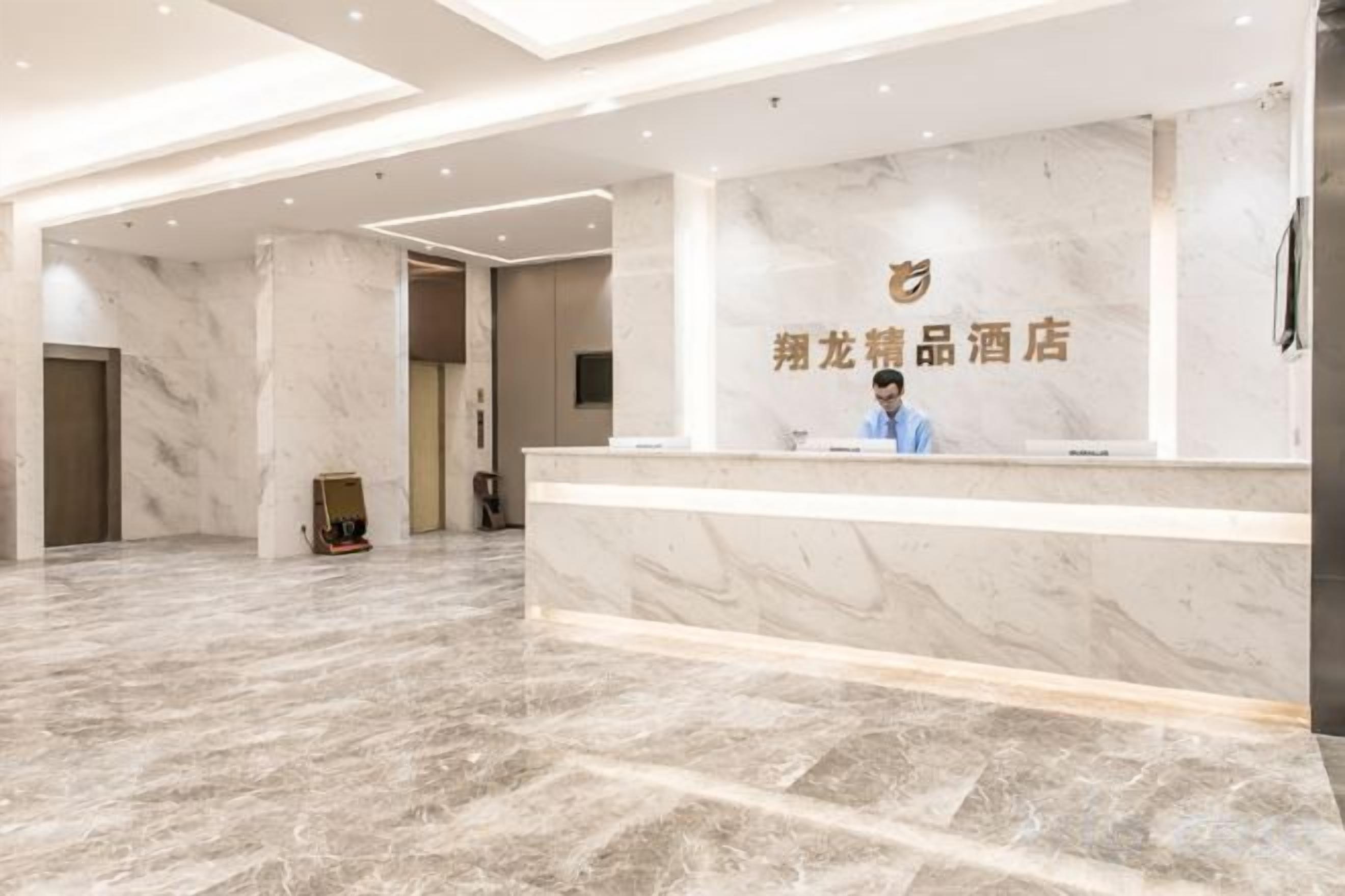 A hotel reception area with a marble floor, a reception desk, and a wall-mounted sign.