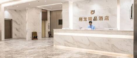 A hotel reception area with a marble floor, a reception desk, and a wall-mounted sign.