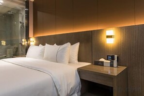 A modern hotel room with a large bed, a bedside table with a lamp, and a glass shower enclosure. - Xianglong Boutique Hotel (Guangzhou North Railway Station Huacheng Road Subway Station) (Guangzhou)