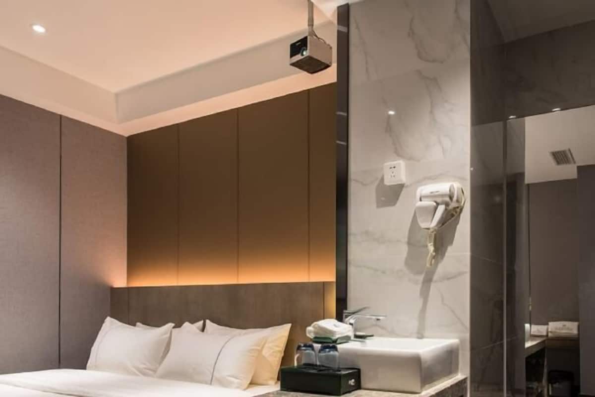Een moderne hotelkamer met een bed, een kaptafel met spiegel en een douche.