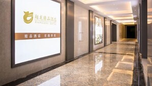 A hotel corridor with a large illuminated sign on the wall, a polished marble floor, and recessed lighting. - Xianglong Boutique Hotel (Guangzhou North Railway Station Huacheng Road Subway Station) (Guangzhou)