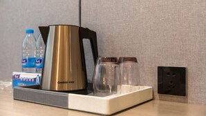 A hotel room with a coffee maker, glasses, a bottle, and a power outlet. - Xianglong Boutique Hotel (Guangzhou North Railway Station Huacheng Road Subway Station) (Guangzhou)