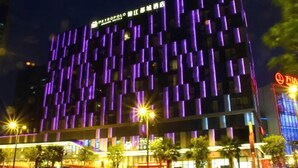 Un hotel moderno con fachada tipo entramado y señalización iluminada.