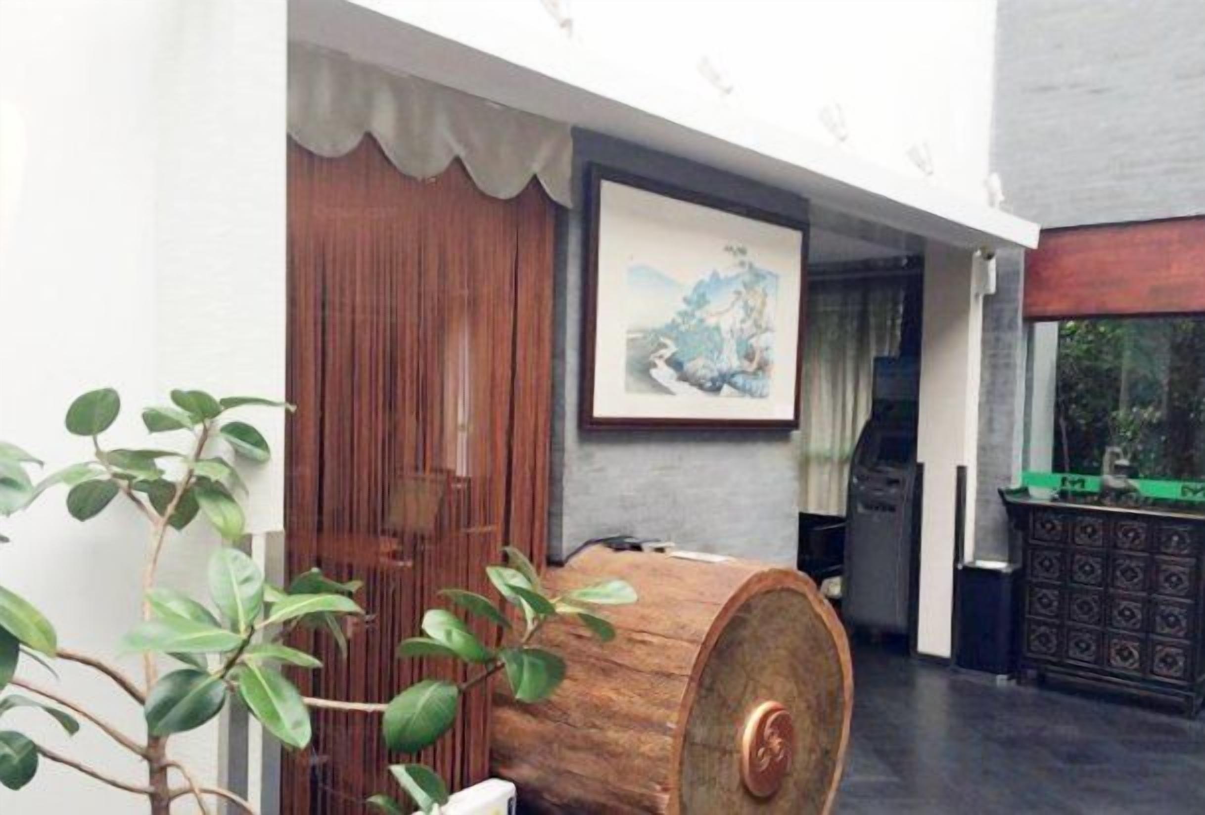 A traditional wooden door, a framed artwork on the wall, and a large barrel in a room with a dark floor.