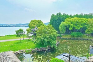 A serene lakeside park with a traditional pavilion, lush greenery, and a calm water body.