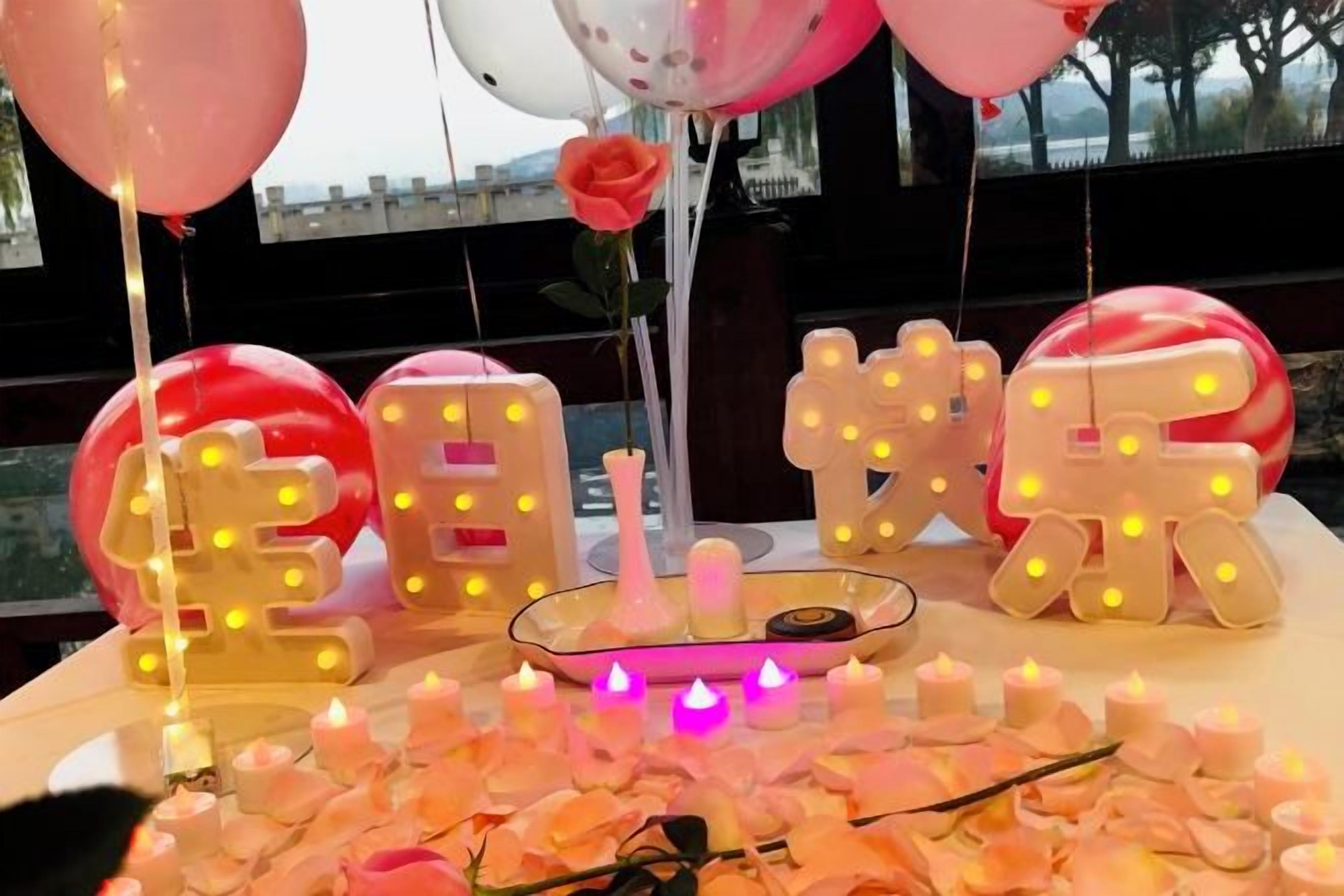 A table with illuminated letters, balloons, and candles.