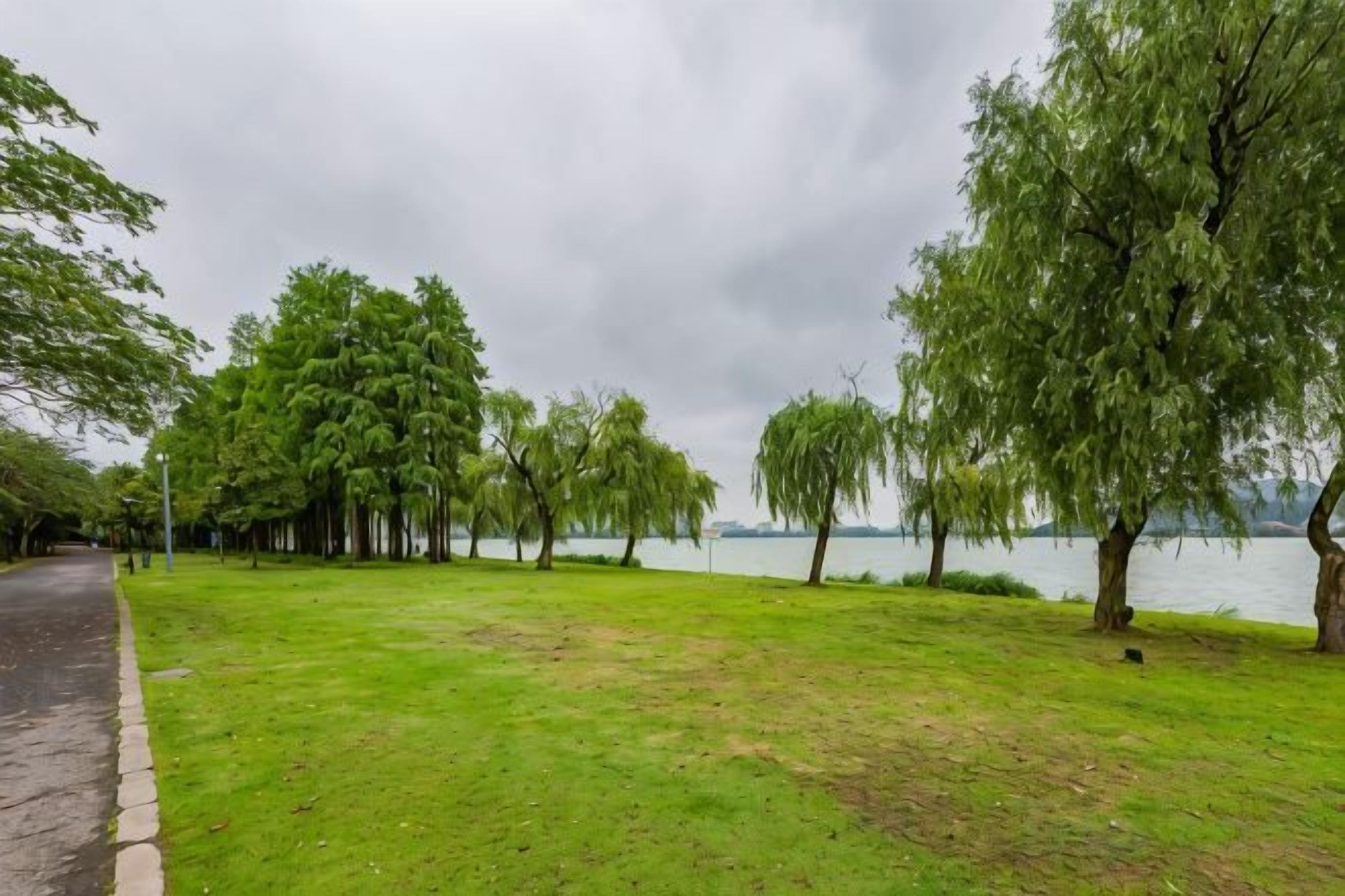 Ein Park mit befestigtem Weg, Rasenflächen und Bäumen.